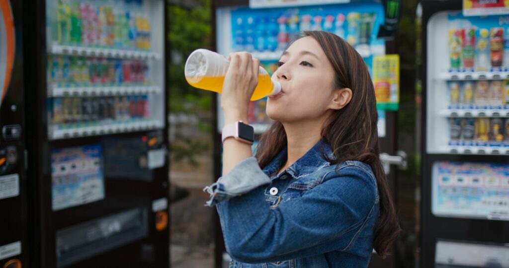 Woman drink a bottle of juice at vending machine